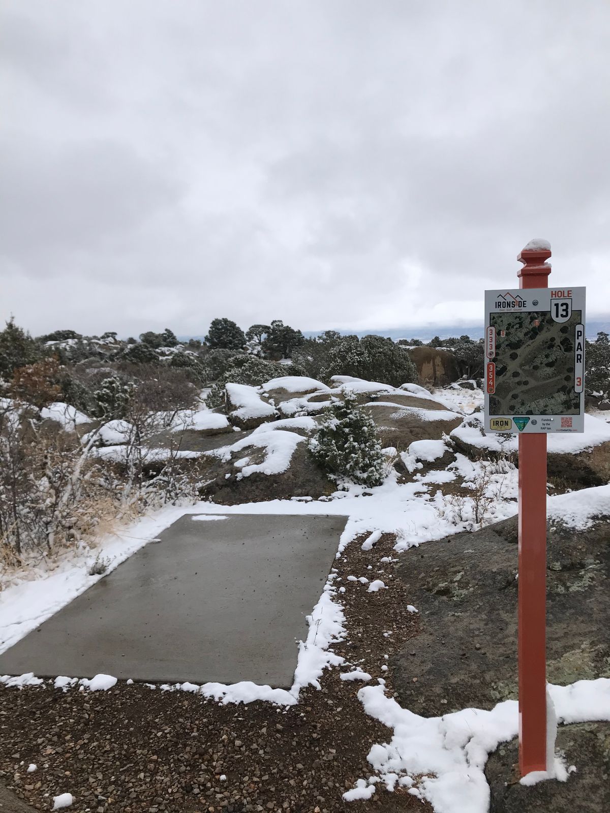 Concrete tee pad and hole signage in winter snow at Ironside